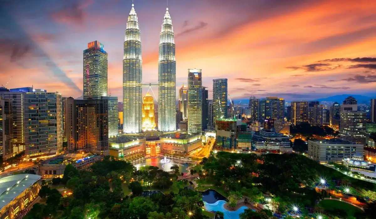 Sunset over Kuala Lumpur with Petronas Towers and city buildings.