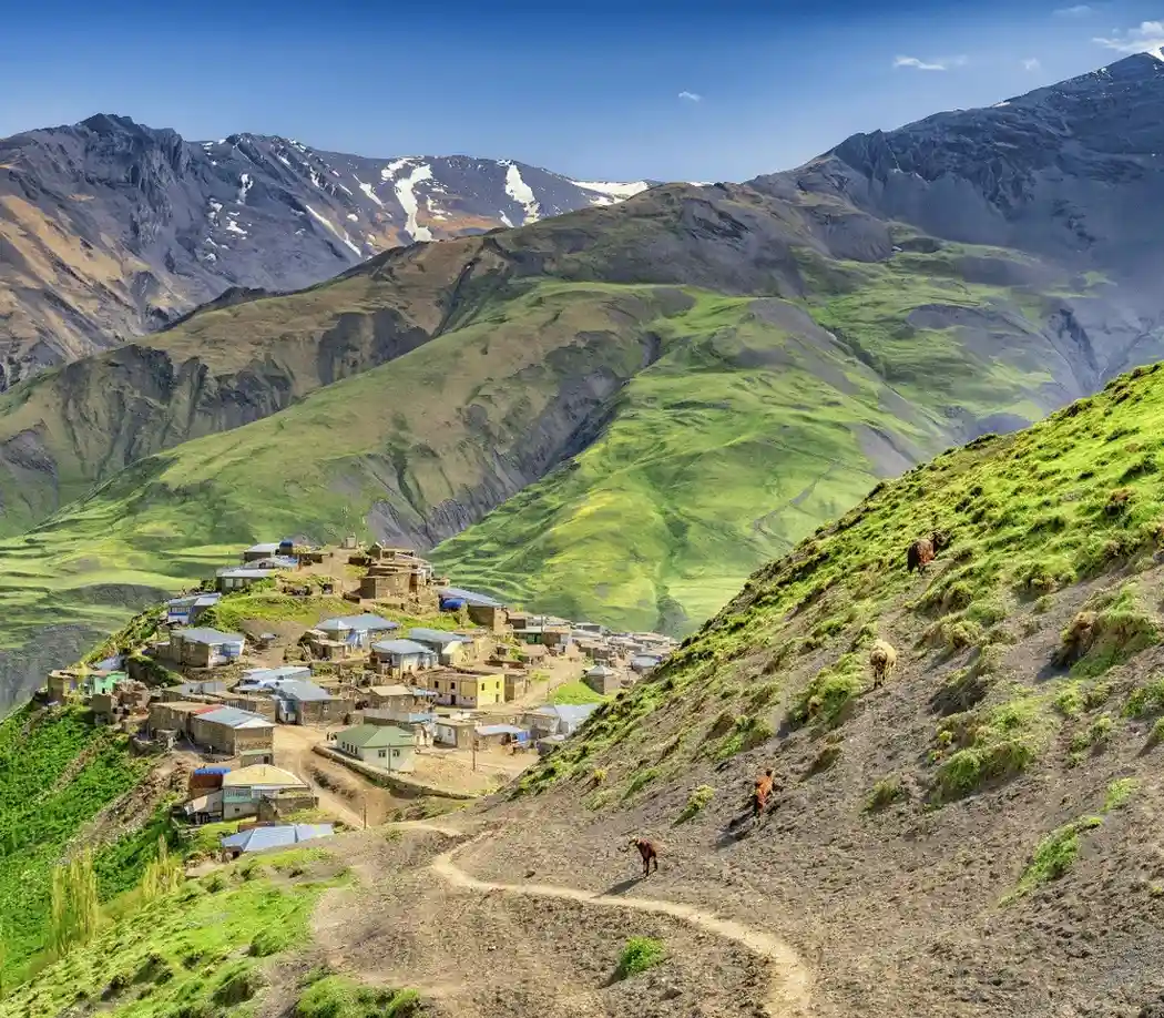 Mountain village of Xinaliq in Azerbaijan with green hills and snow-capped peaks