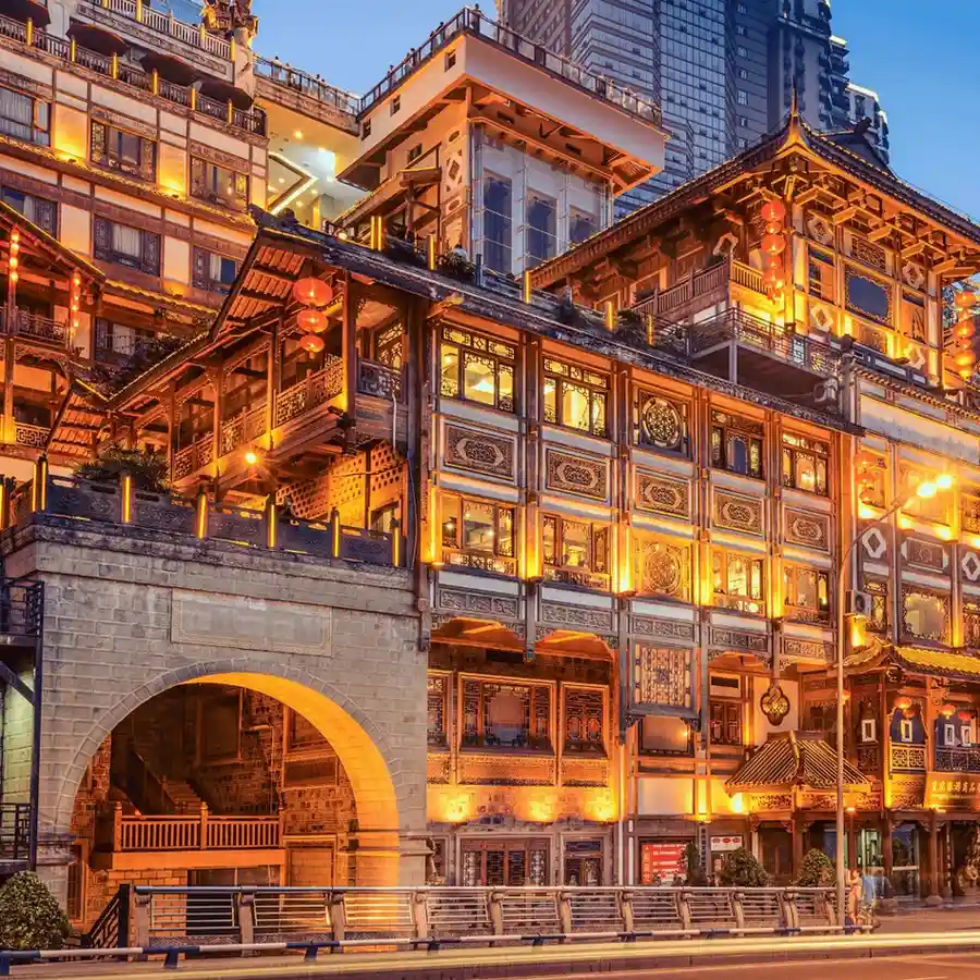 Illuminated Hongya Cave in Chongqing, China at night with traditional architecture.